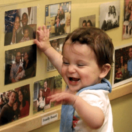 Toddler child standing at family board photos