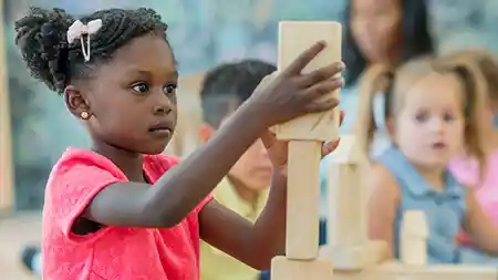 Preschool girl building with wood blocks